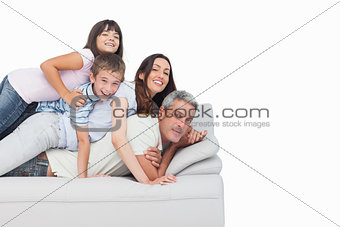 Smiling children lying on their parents on sofa