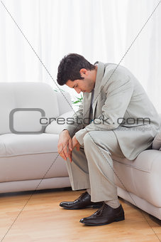 Troubled buinessman sitting on sofa lowering his head