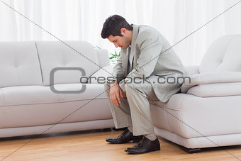 Unhappy buinessman sitting on sofa lowering his head
