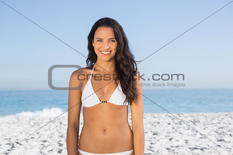Smiling pretty long haired woman in white bikini posing