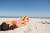 Beautiful young brunette in pink bikini sunbathing