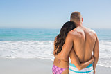 Cute couple hugging while looking at the sea