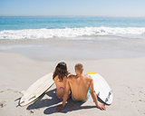 Young couple with their surfboards looking at the sea