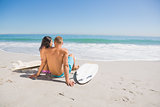 Pretty young couple with their surfboards looking at the sea