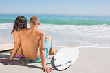 Cute young couple with their surfboards looking at the sea