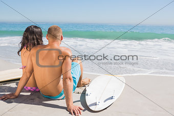 Cute young couple with their surfboards looking at the sea