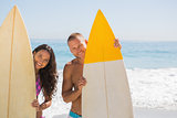 Cute young couple holding their surfboards
