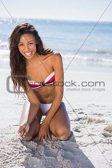 Smiling young sexy woman touching sand