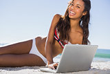 Happy attractive young woman in bikini with her laptop