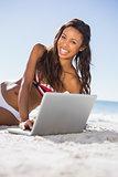 Cheerful attractive young woman in bikini with her laptop