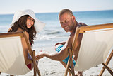 Cute couple looking at camera while lying on their deck chairs