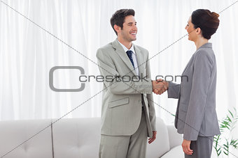 Smiling colleagues shaking hands during meeting