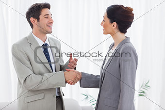 Happy colleagues shaking hands during meeting