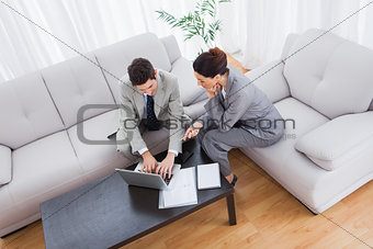 Colleagues working together sitting on sofa and using laptop