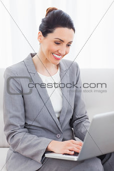 Busineswoman using laptop sitting on sofa