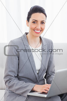 Smiling busineswoman using laptop sitting on sofa