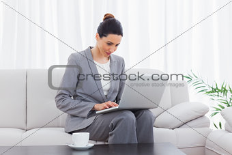 Busineswoman sitting on sofa using laptop