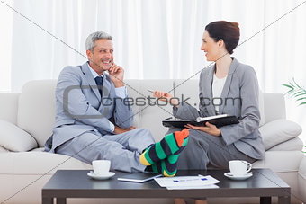 Funny businessman wearing stripey socks and laughing with his colleague