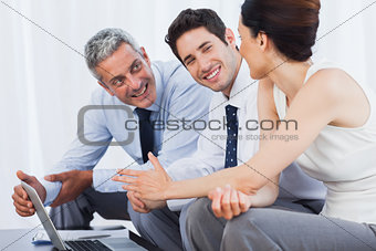 Smiling business people working with their laptop on sofa