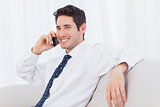 Businessman calling with his mobile phone on sofa