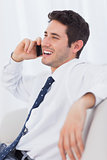 Happy businessman calling with his mobile phone on sofa