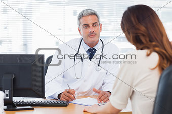 Doctor listening to his patient talking about her illness