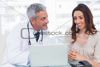 Docter showing something on laptop to his patient