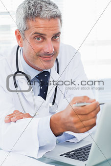 Smiling doctor watching something on his laptop