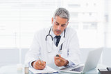Doctor holding medication and writing a prescription