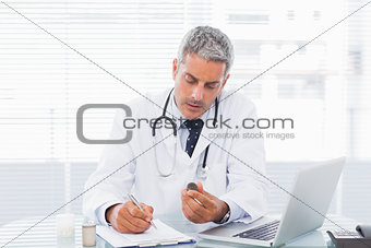 Doctor holding medication and writing a prescription