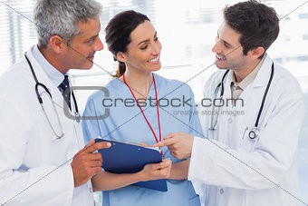 Smiling nurse and doctors looking together a file