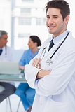 Smiling doctor looking at camera with colleagues behind