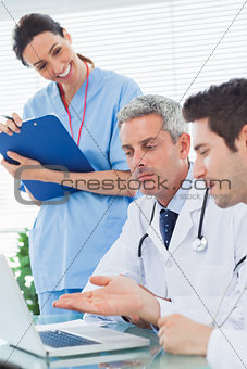 Smiling nurse listening to doctors talking about something on their laptop
