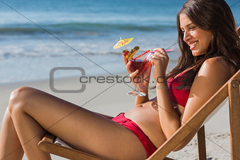 Happy woman drinking cocktail while relaxing on her deck chair
