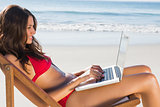 Attractive woman using her laptop while relaxing on her deck chair