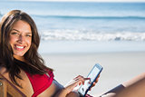 Smiling woman using her tablet while relaxing on her deck chair