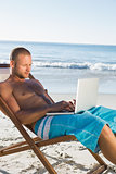 Handsome man using his laptop sitting on his deck chair