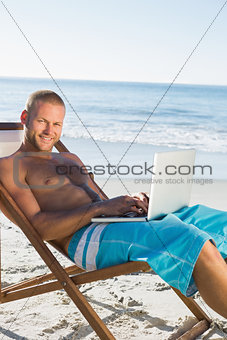Handsome man using his laptop while sunbathing