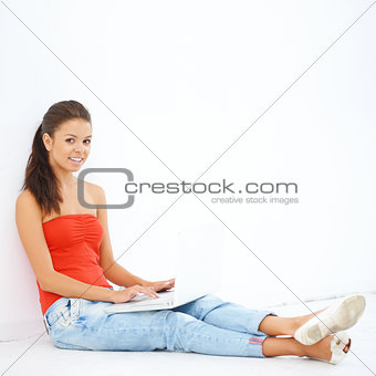 Young smiling girl sitting on the floor with laptop