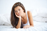 Brunette woman lying on bed in bad mood