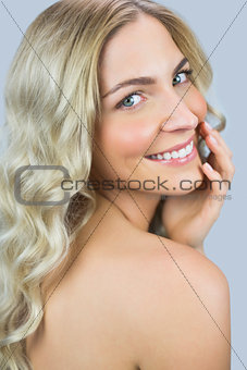 Smiling gorgeous blond model posing while touching her face