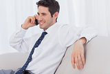 Businessman smiling and calling on sofa