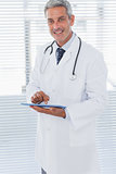 Smiling doctor holding his tablet pc and looking at camera
