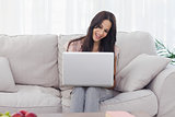 Attractive brunette using her laptop and smiling