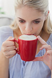 Blonde woman holding a mug and sipping from it