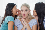 Friends telling secret to blonde woman