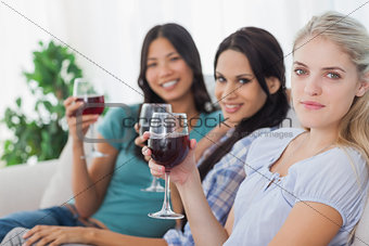 Cheerful friends having red wine together looking at camera