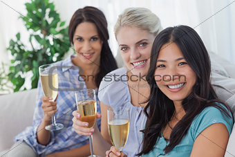 Happy friends enjoying champagne together looking at camera