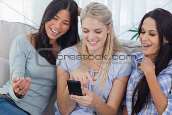Laughing friends looking at smartphone