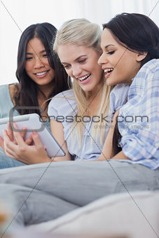 Smiling friends using digital tablet together